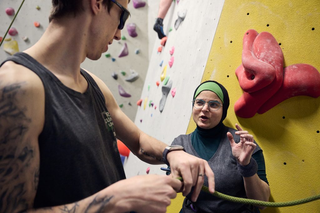 Coach and climber at bottom of climbing wall talking