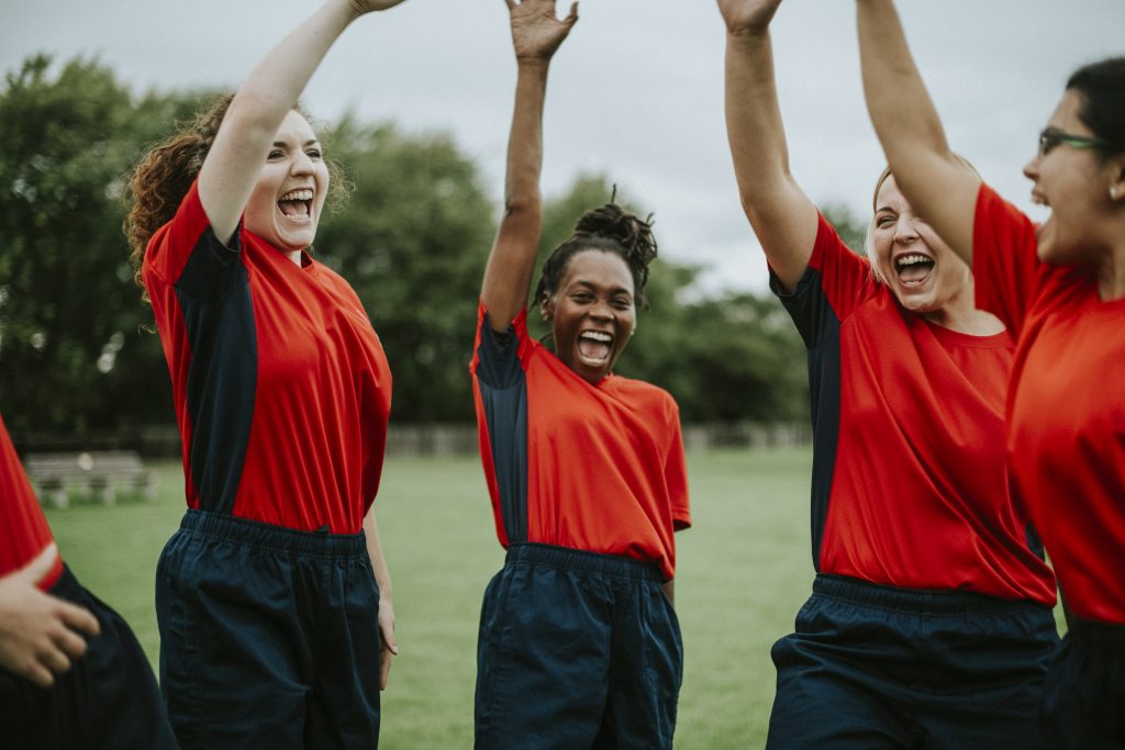 four young women in red tops with hands up