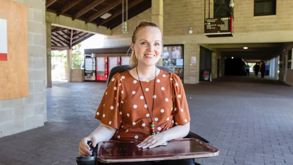Graduate sitting at a small desk in a large indoor open space