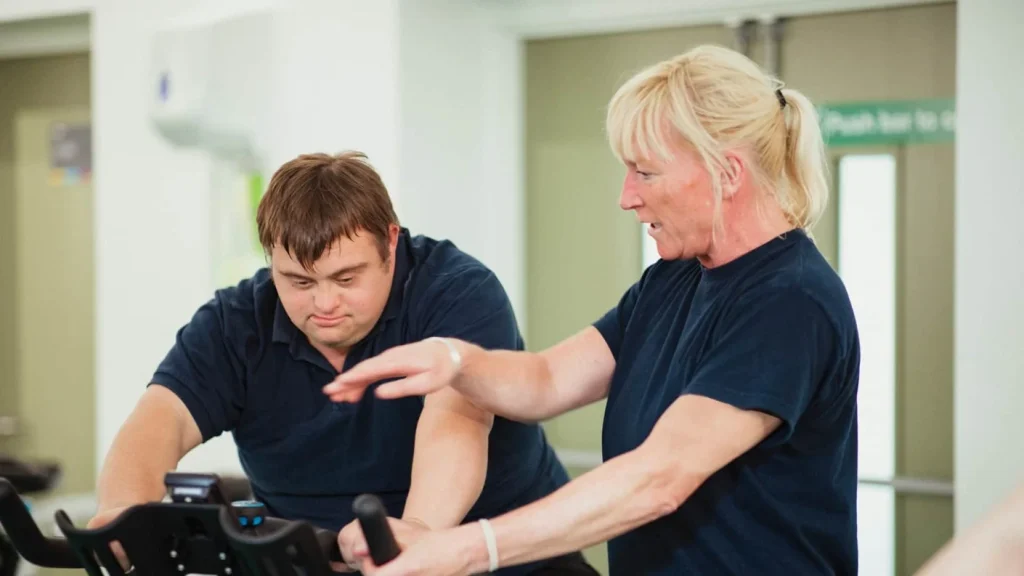 Gym instructor providing instructions to a client on an exercise bike