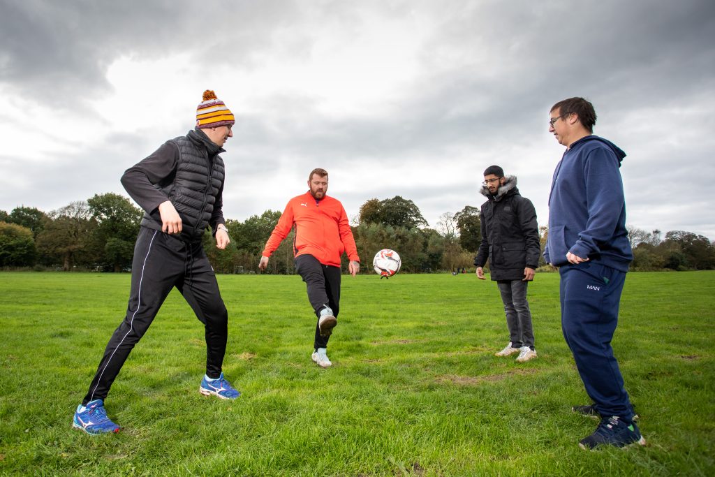Four men having a kickabout on football field