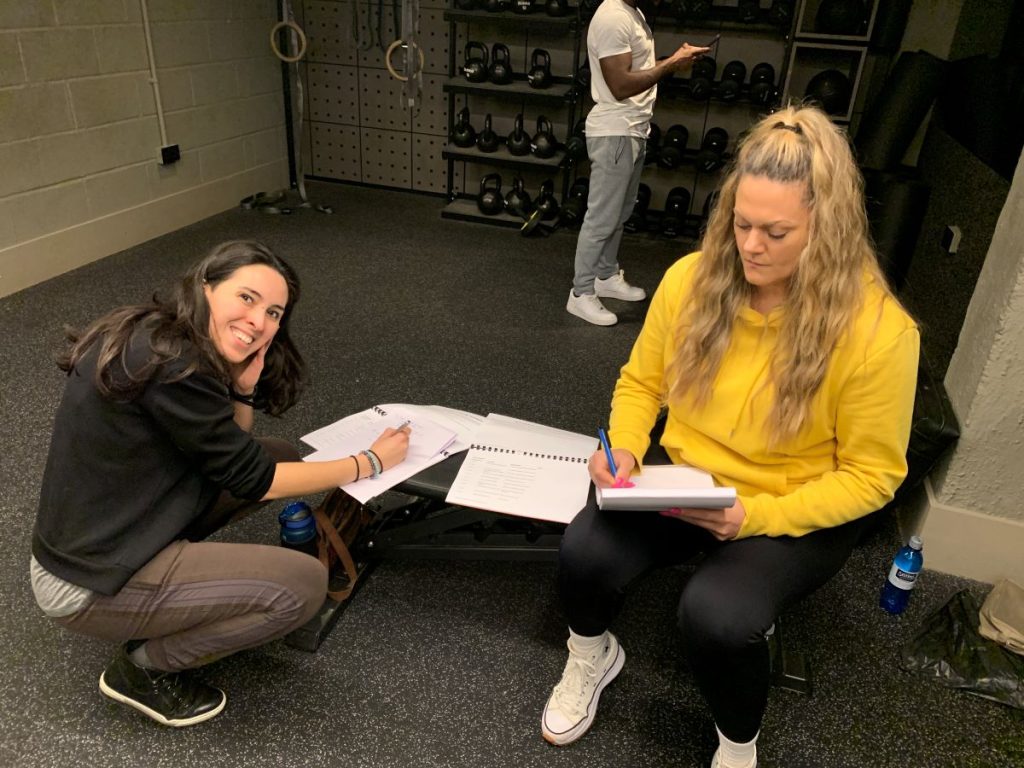 Two course participants taking notes in a gym