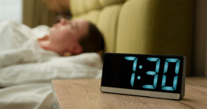 Woman laying in bed awake next to alarm clock